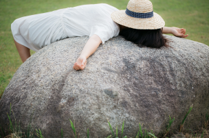 大きな石の上で寝転ぶ女性